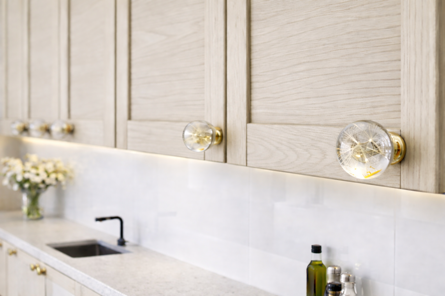 Modern kitchen with light wood cabinets, dandelion resin knobs with golden base