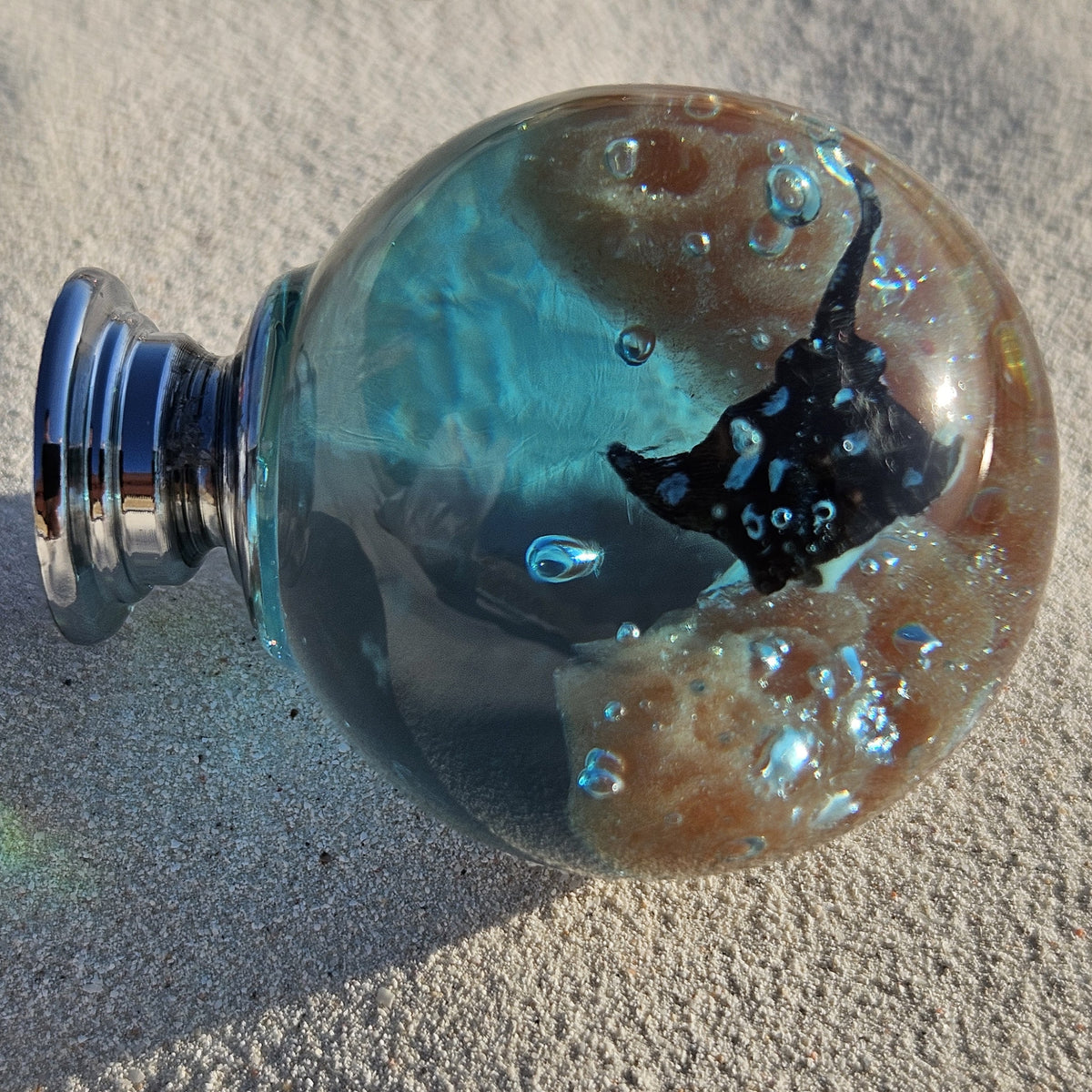 Ocean-inspired stingray cabinet knob in turquoise resin photographed on sand
